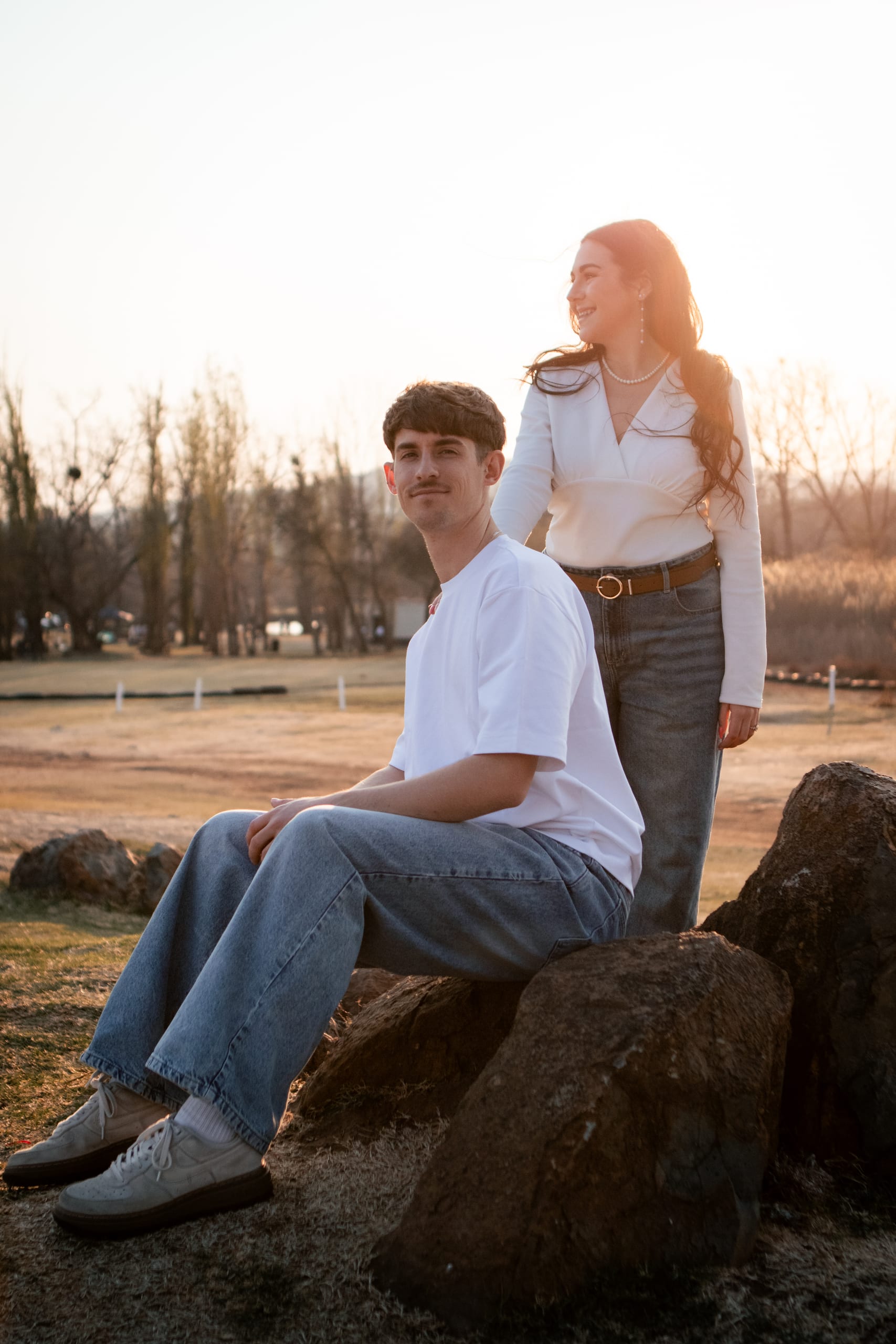 Gareth seated on a rock with Shannon standing behind him in warm afternoon light
