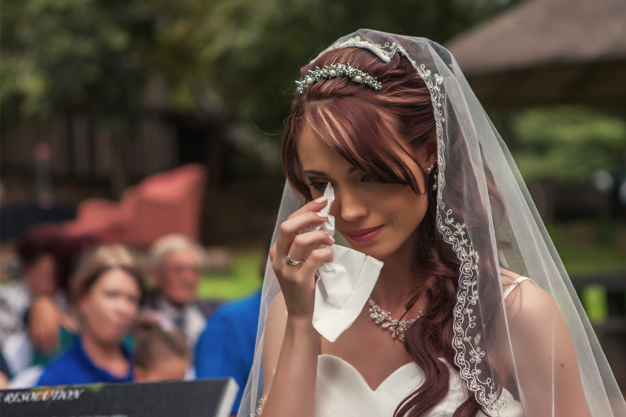 Bride wiping away a tear during her wedding ceremony
